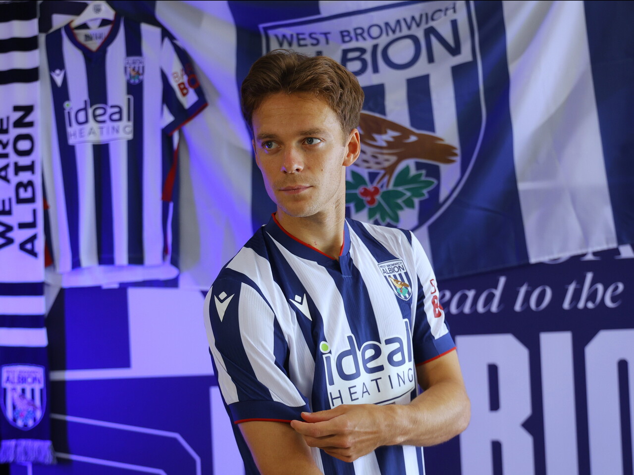 Felix Horn Myhre looking towards the camera while stood in the home kit in front of WBA branding