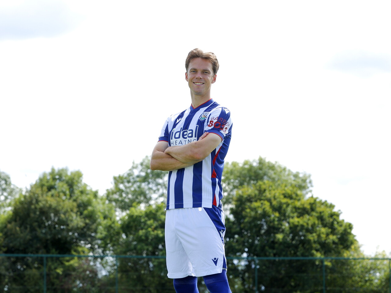 Felix Horn Myhre smiling at the camera with his arms folded while stood in the home kit 