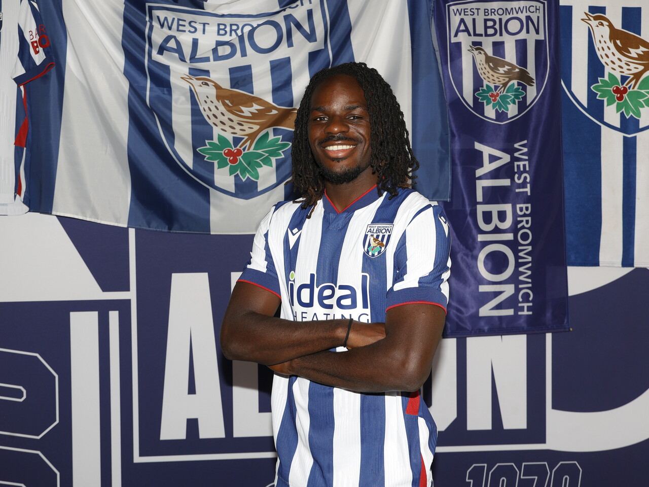 Brayann Pereira smiling at the camera while stood in the home kit in front of WBA branding 