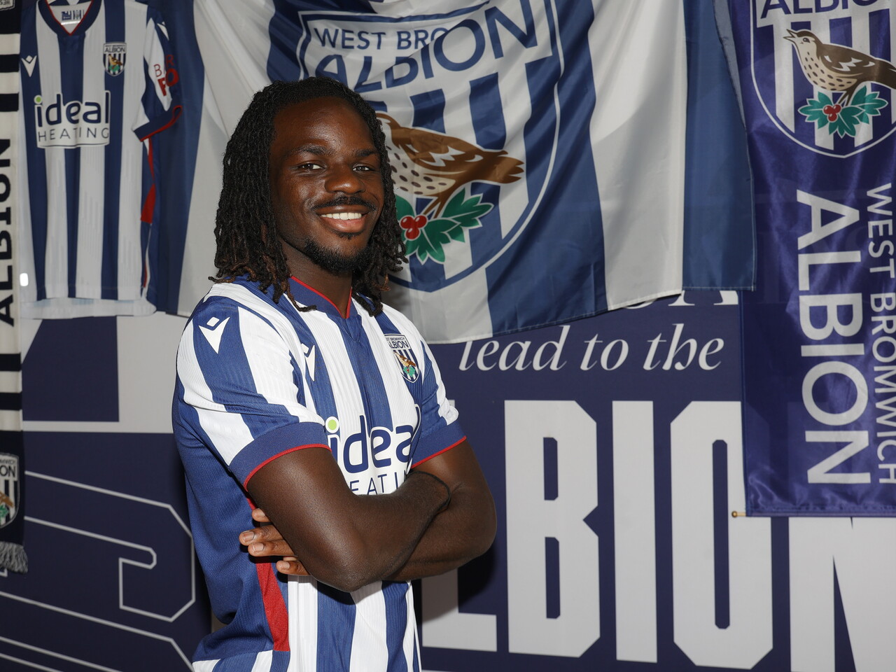 Brayann Pereira smiling at the camera while stood in the home kit in front of WBA branding 