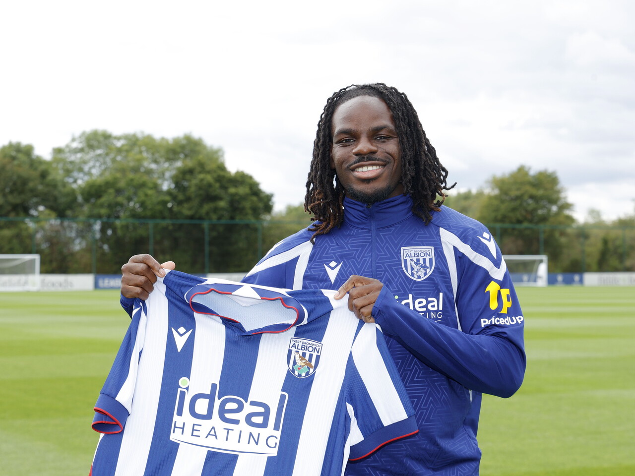 Brayann Pereira smiling at the camera while holding up a home WBA shirt