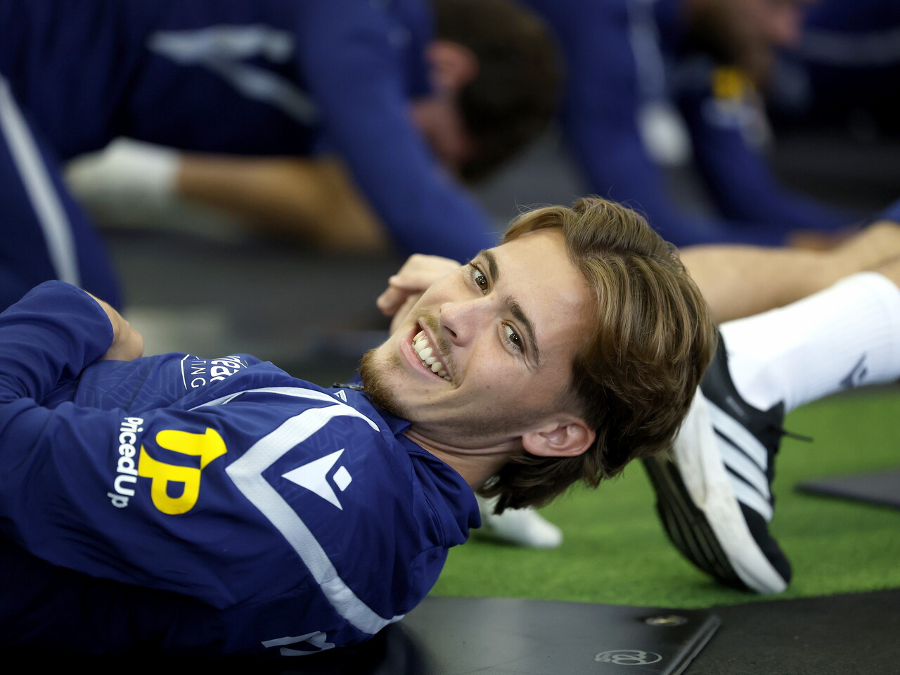 Isaac Price smiling while stretching on his back in the gym