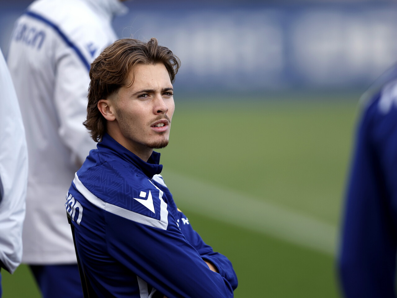 Isaac Price sat down on the side of the training pitch having a chat with team-mates