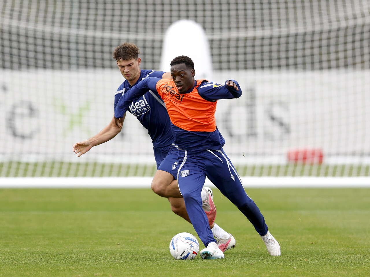 Rabby Nzingoula running with the ball during training, closely marked by Noah DuPont