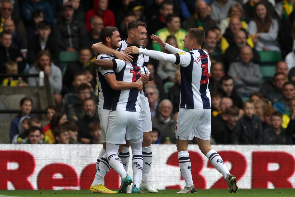 Albion players celebrate a goal while wearing home colours