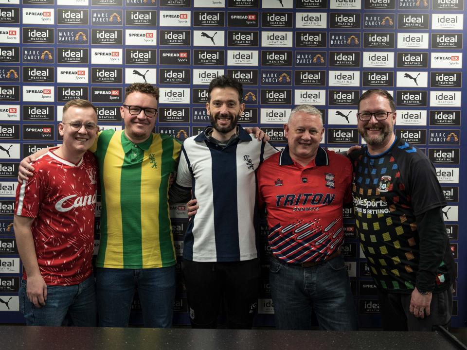 An image of Carlos Corberán wearing a 1978 Albion home shirt, alongside members of the local press