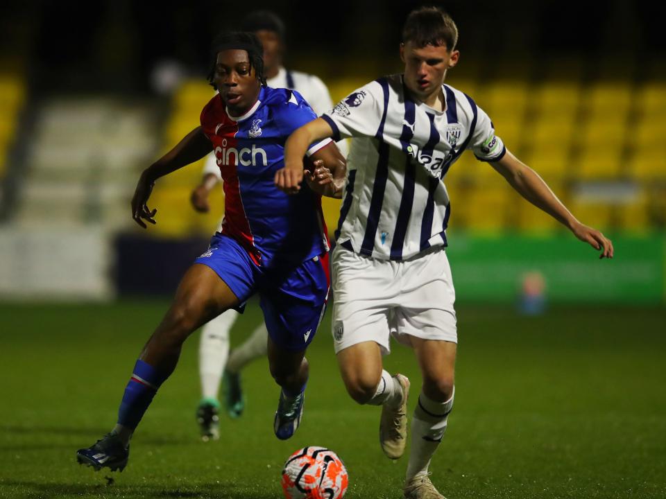 A photo of Albion U21s defender Reece Hall battling for the ball, in the 2023/24 home kit, against a Crystal Palace attacker during a PL2 game at Sutton United's ground