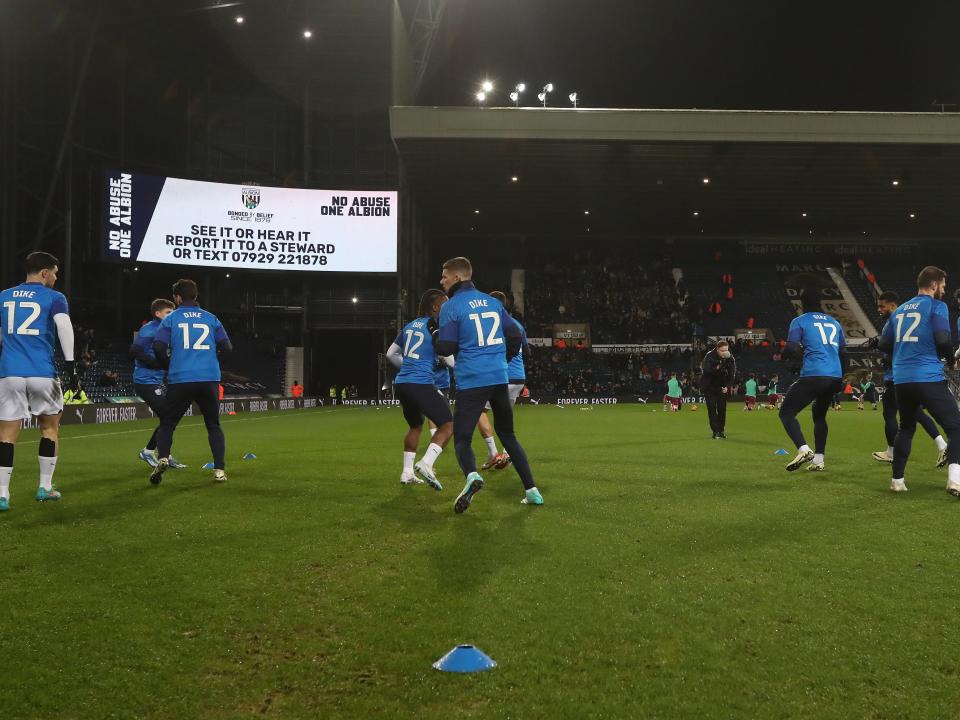 An image of Albion's players warming up in 'Dike 12' shirts