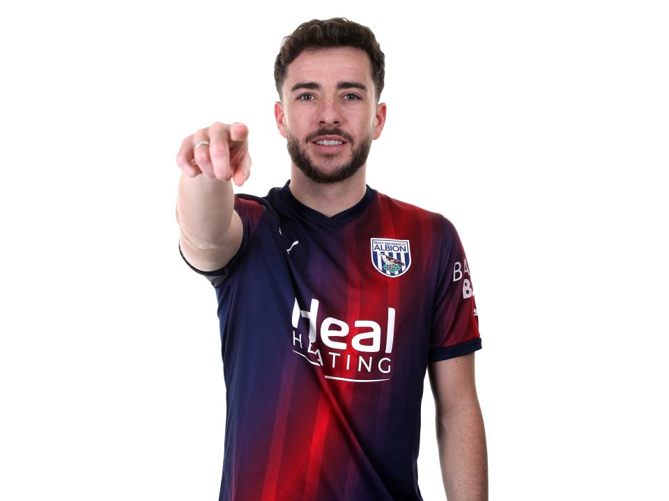Mikey Johnston pointing at the camera while wearing a navy blue and red away shirt