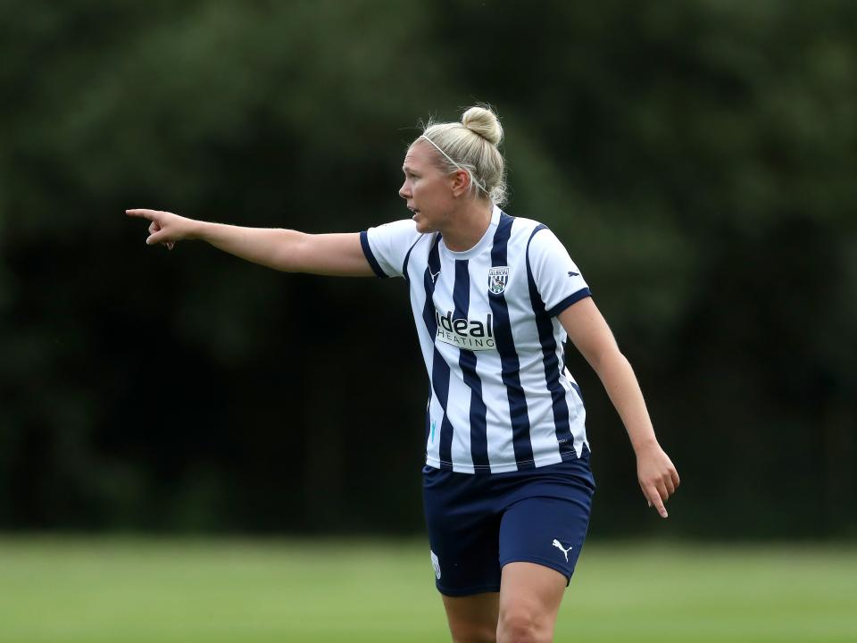 Hannah George pointing to her right in the home kit during a game