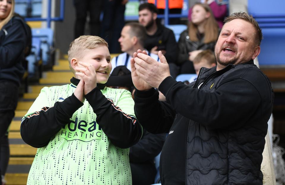 A general view of two Albion fans smiling and clapping 