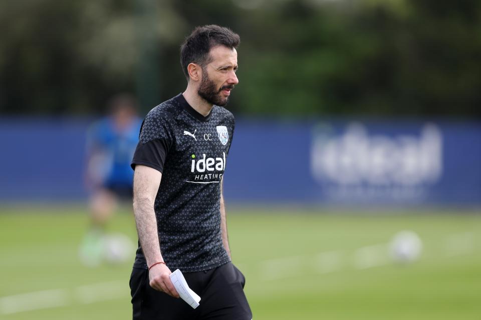 Carlos Corberán holding a note out on the training pitch