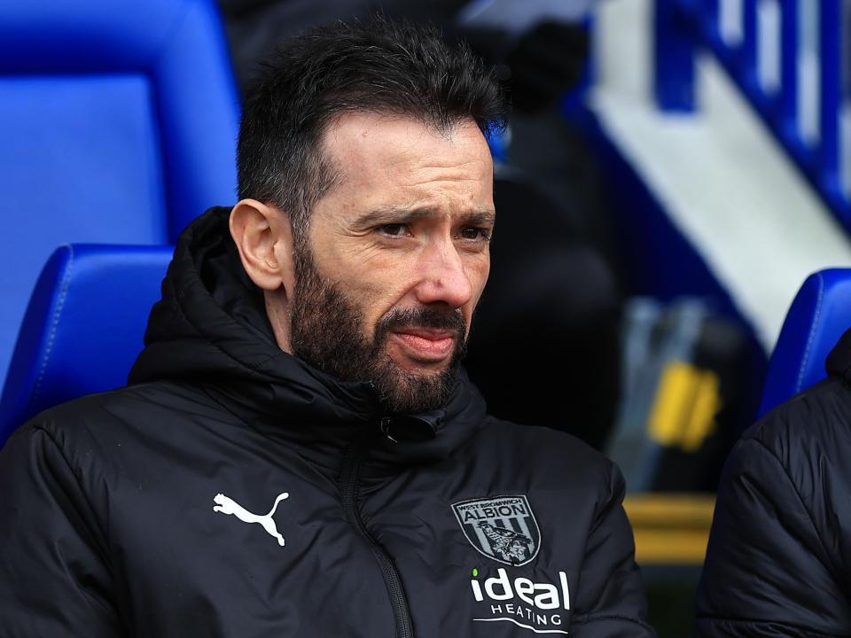 Carlos Corberán watches an Albion game while wearing a black coat