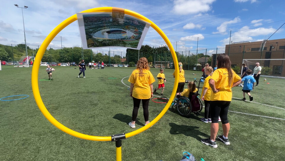 Student participating in activities with a hole on a stick in the forefront of the photo.