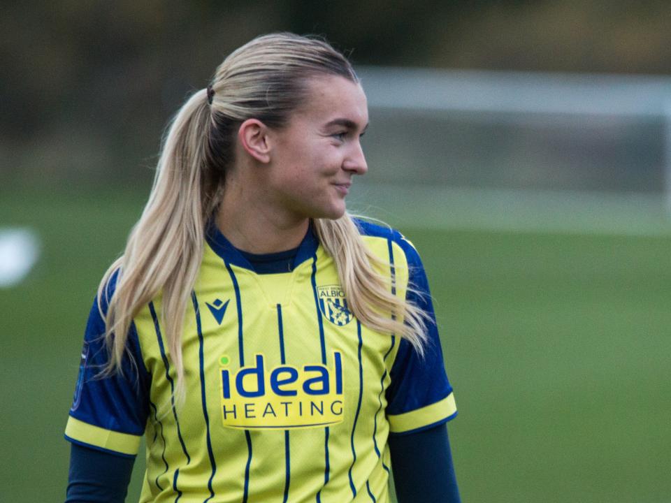 Taylor Reynolds smiling while looking to her left while wearing the yellow away shirt 