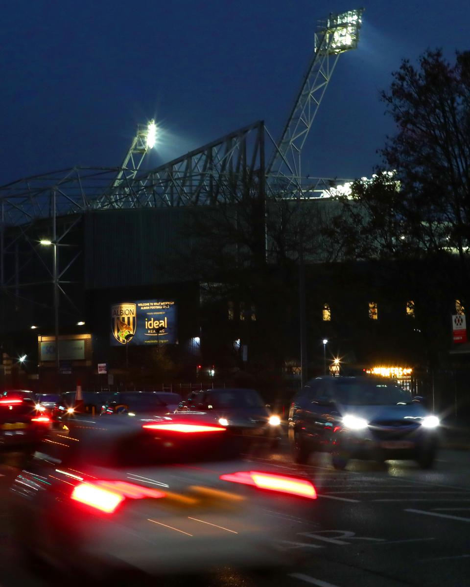 An image of The Hawthorns floodlights and road cars