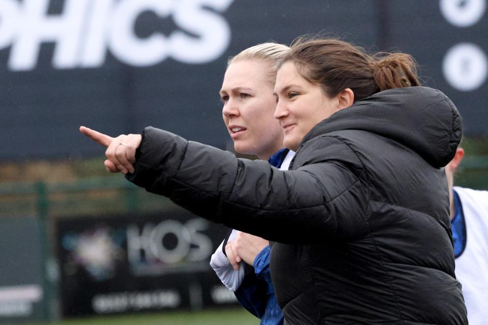 Siobhan Hodgetts-Still on the side of the pitch smiling and pointing 