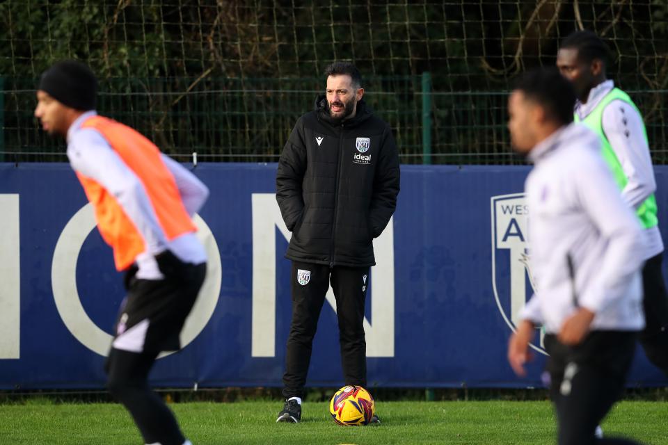 Carlos Corberán watching training while stood with a yellow ball at his feet 
