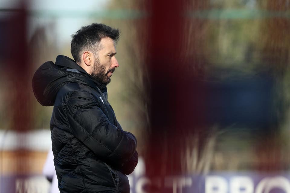 Carlos Corberán with his arms folded watching training wearing a big coat 