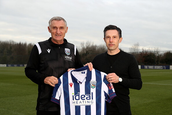 Tony Mowbray and Andrew Nestor smiling at the camera while holding a home shirt out on a training pitch 