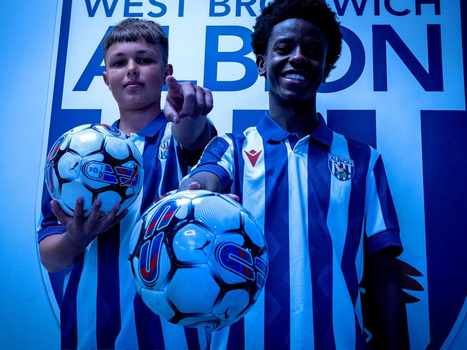 Two players posing in front of the WBA badge.