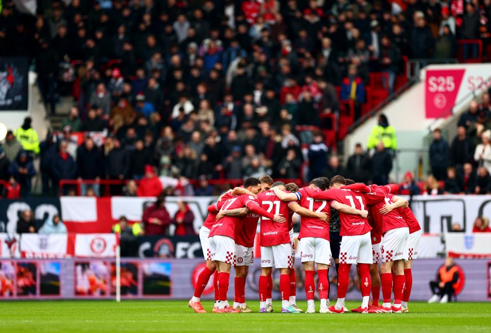 Bristol City players in the home kit in a pre-match huddle out on the pitch 
