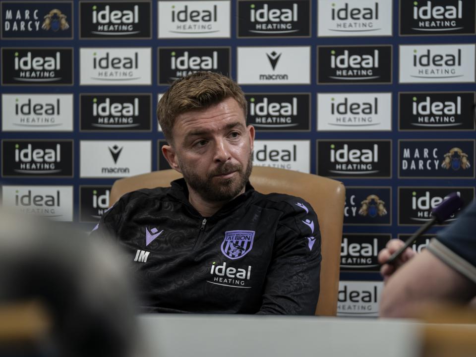 James Morrison is interviewed by the media in front of the press conference sponsor board