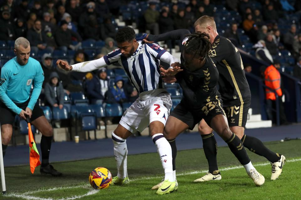 Darnell Furlong holding off two Coventry City players in the corner during a match at The Hawthorns