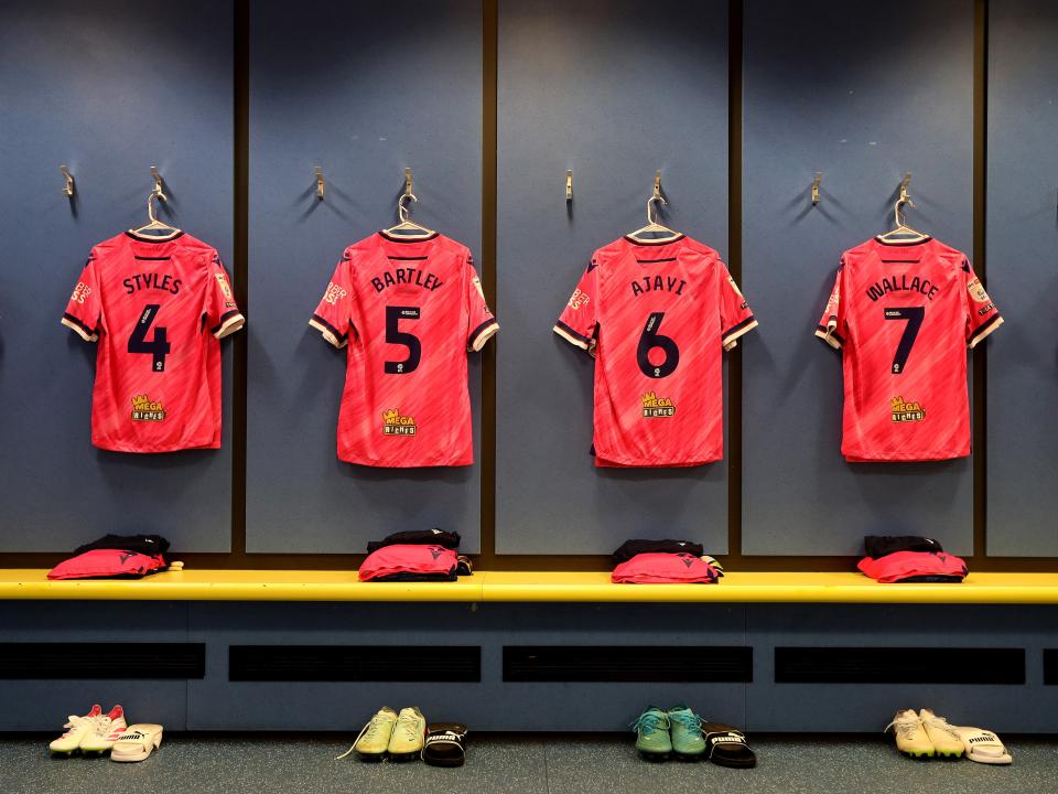 An image of four pink Albion shirts hanging up in the dressing room