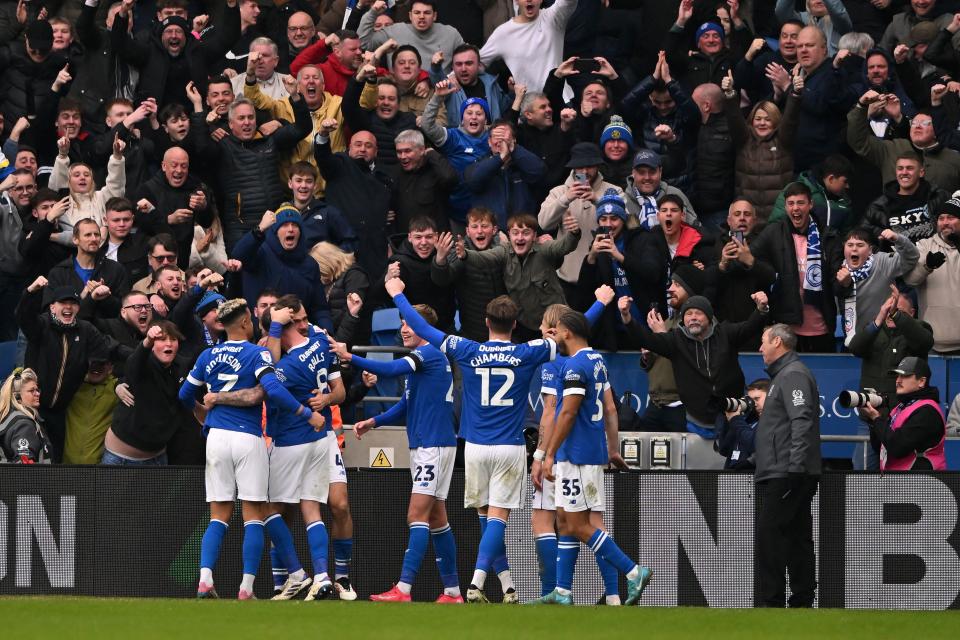 Several Cardiff City players in the home kit celebrate a goal in front of their fans who also celebrate