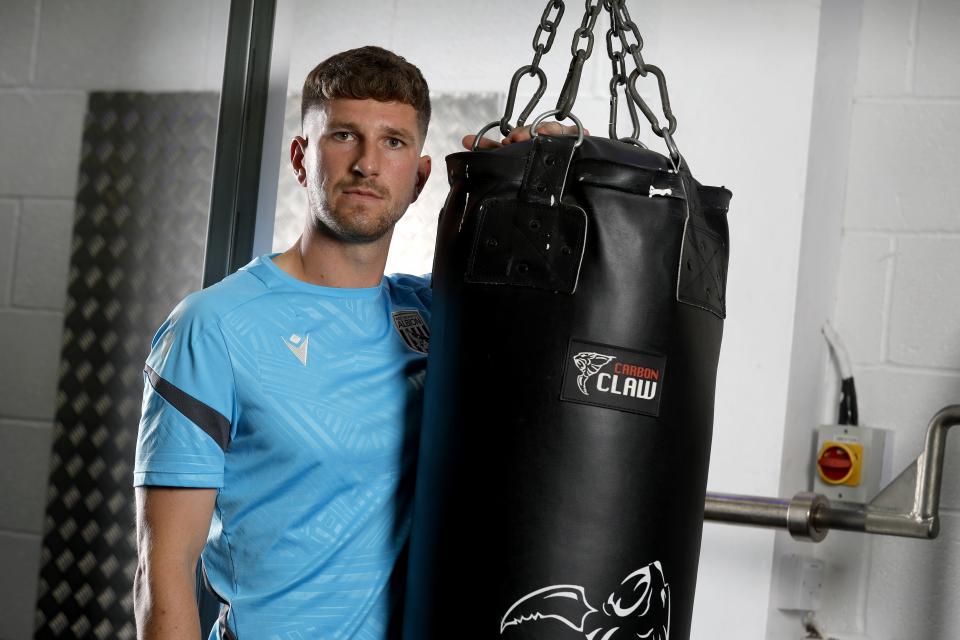 Chris Mepham leaning on a punch bag in the gym looking at the camera 