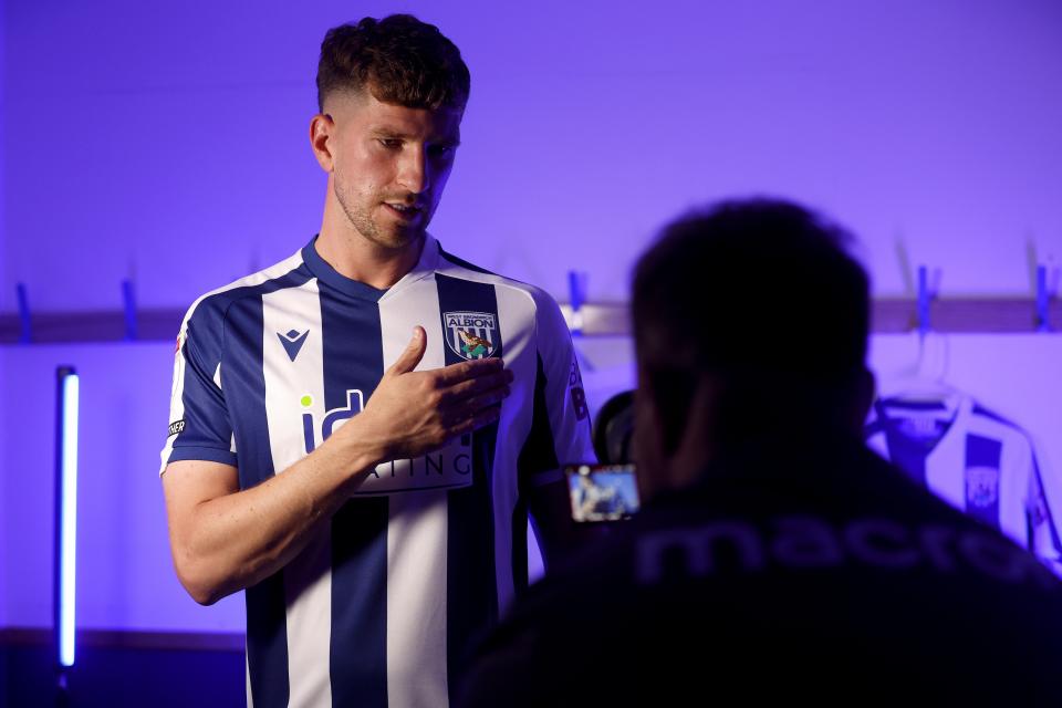 Chris Mepham in a home shirt is filmed tapping the WBA badge 