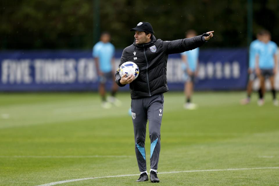 Ryan Mason pointing to the left while holding a ball during a training session