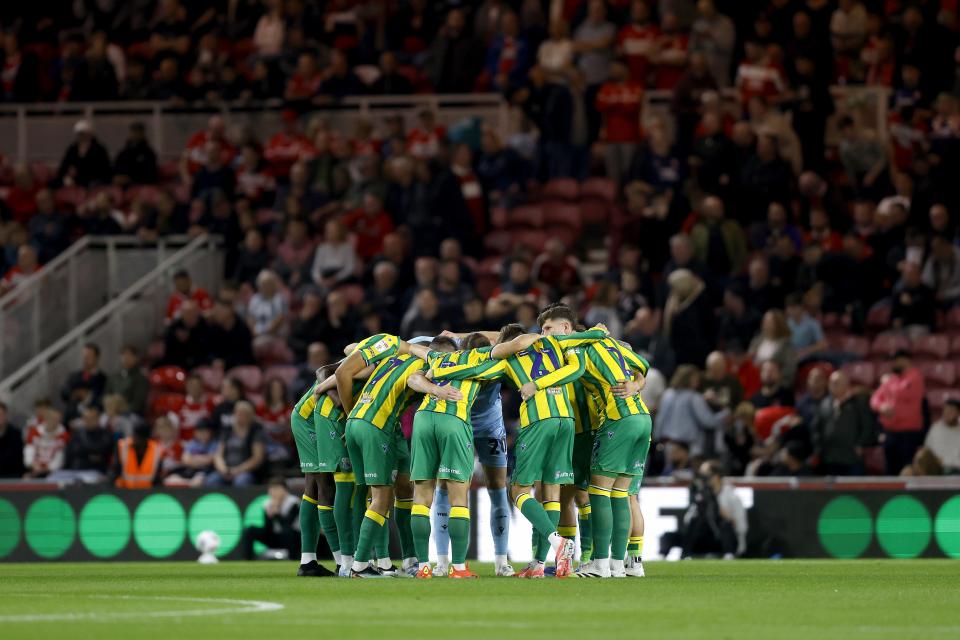 Albion in a pre-match huddle before a game in the yellow and green away kit 
