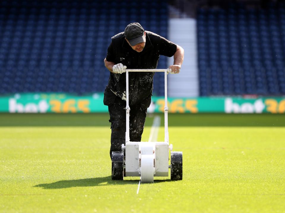 A photo of Albion groundsman Rob Lane drawing out lines at The Hawthorns
