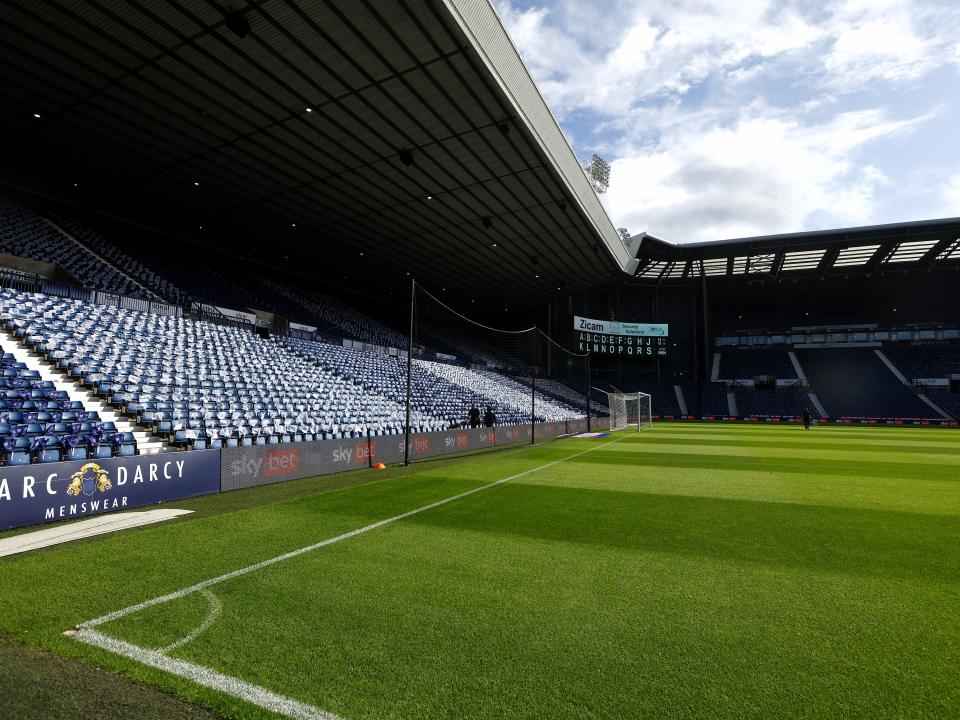 An image of The Hawthorns, with the Woodman Corner scoreboard back, and flags laid out around the stadium