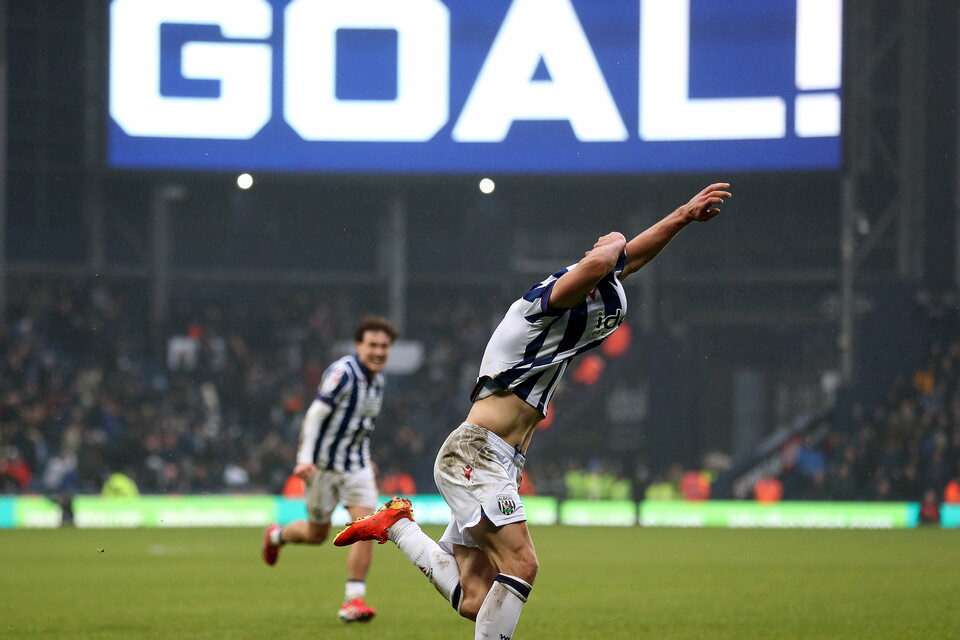 Jayson Molumby celebrates by pulling his top off with 'GOAL' written on the big screen behind him