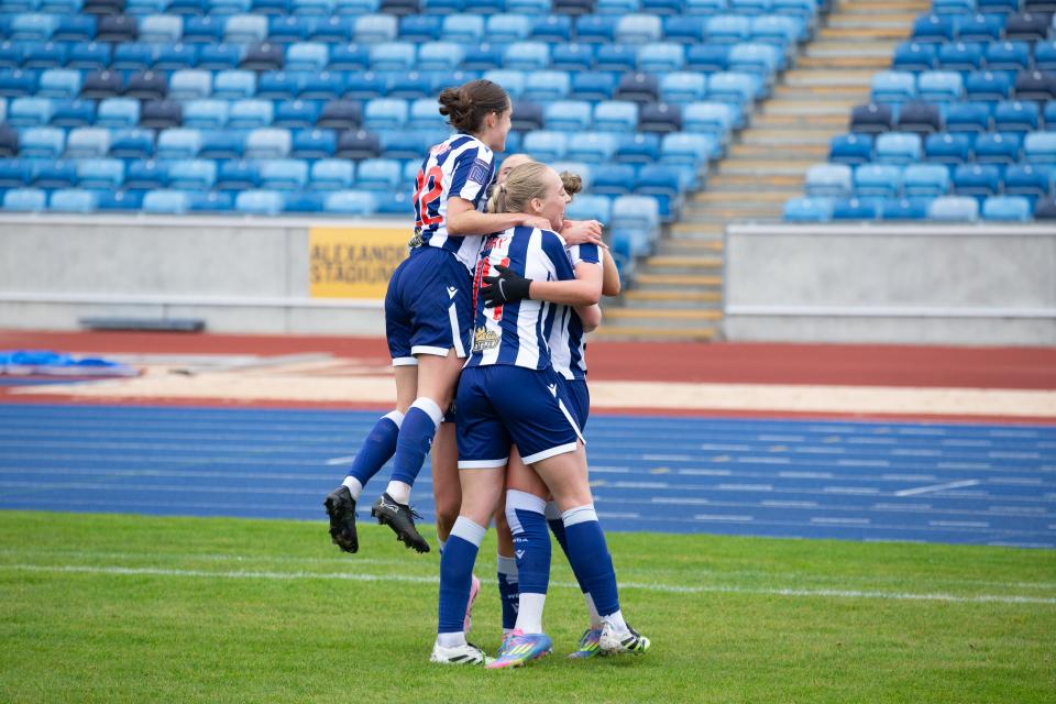 Albion Women players celebrate in the home kit after a goal is scored 