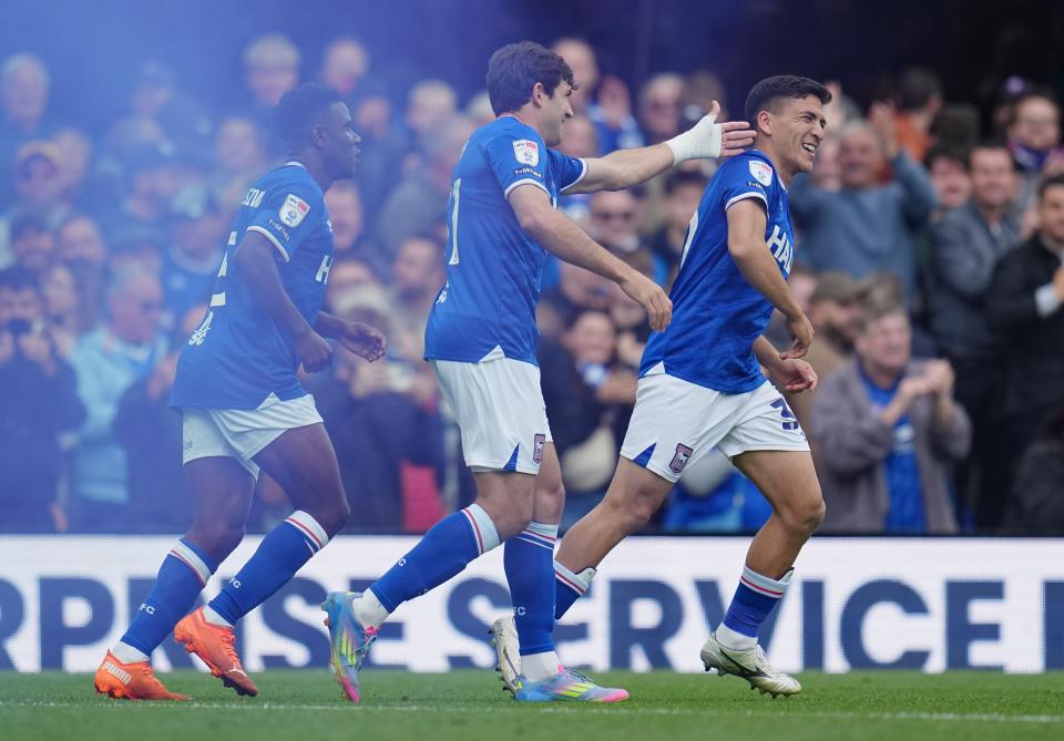 Three Ipswich players celebrating a goal in their home kit 