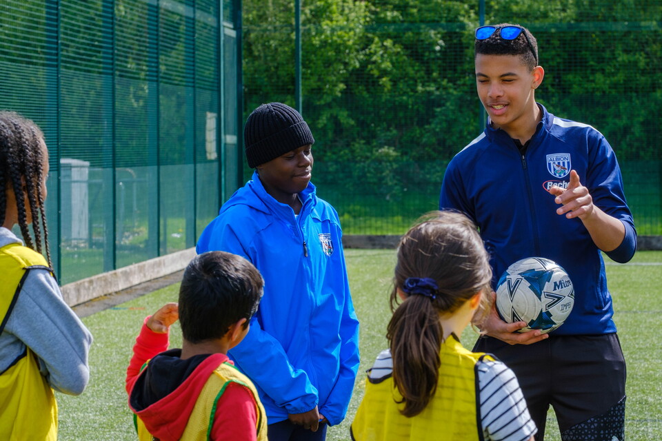 Two volunteers speaking with a small group of children
