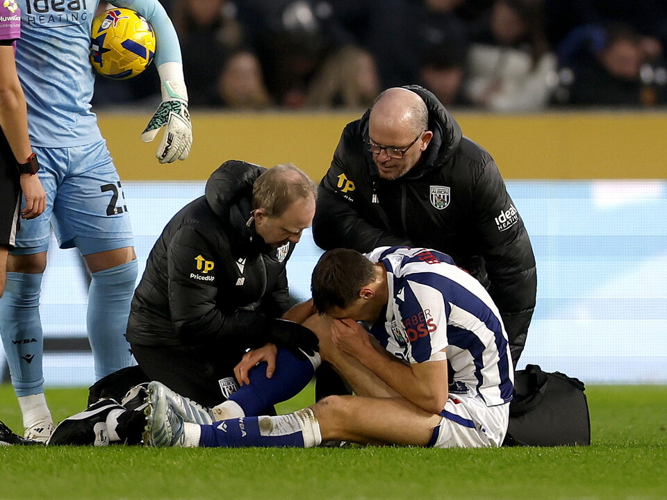 Krystian Bielik is assessed by medical staff on the pitch after picking up an injury 