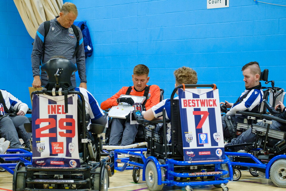 Chris Gordon holding a tactics board discuss strategy with the team