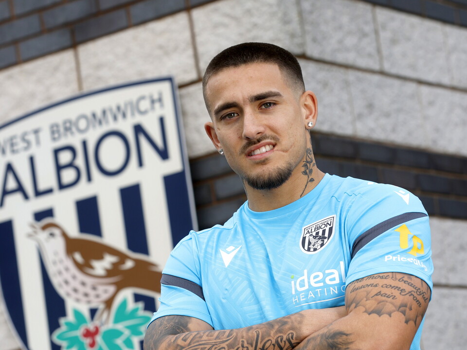 Danny Imray smiling at the camera while stood in front of a WBA badge on a wall