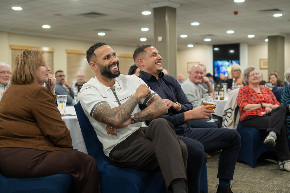 Bartley and Livermore seated with the audience and laughing