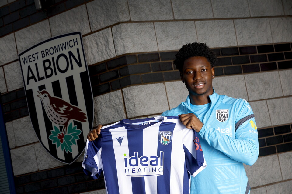 Jamaldeen Jimoh-Aloba smiling at the camera while holding a home shirt up 