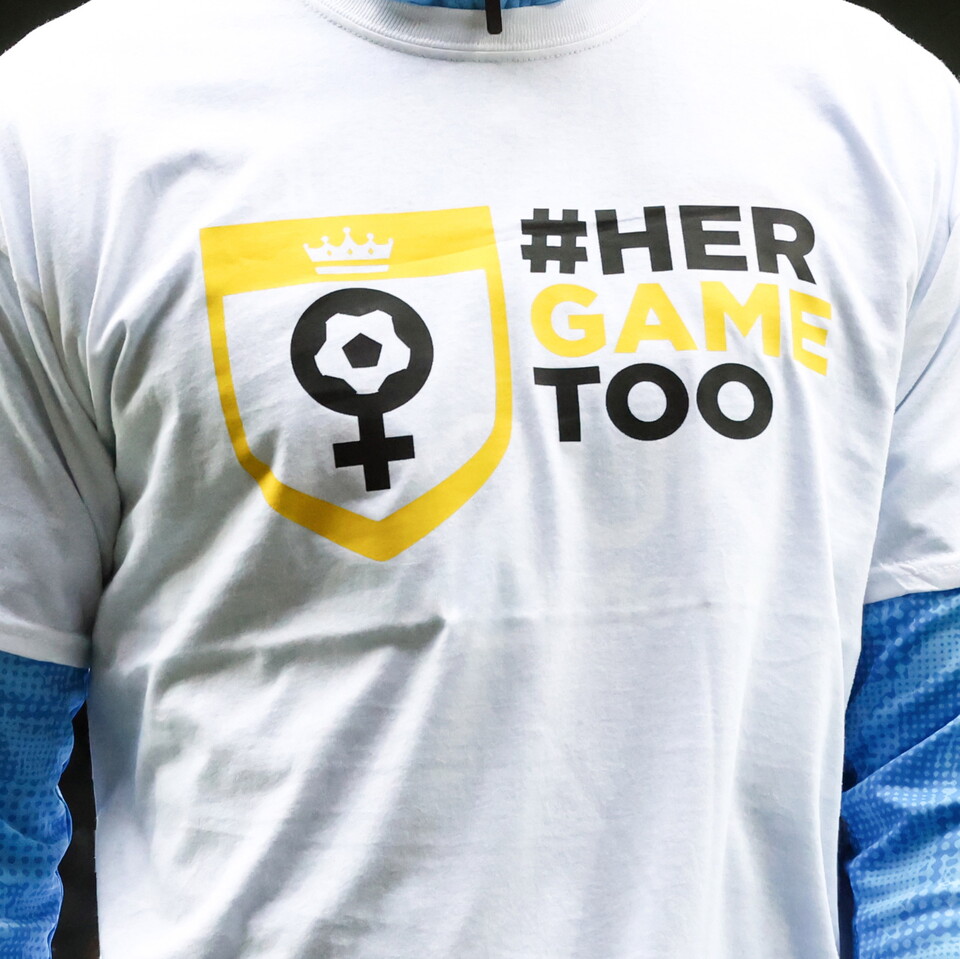 A white t-shirt with the Her Game Too logo on it