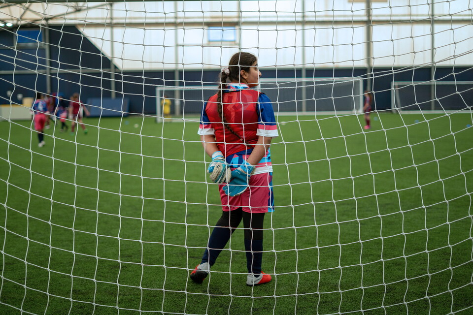 Close up of goalkeeper from behind the goal with players in the background.