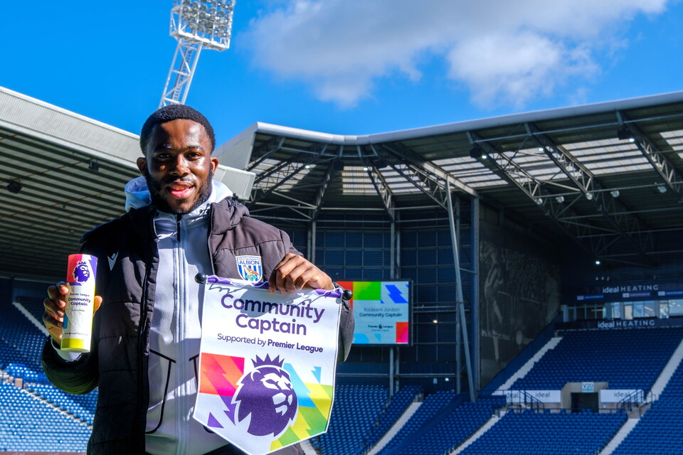 Kadeem Jordan holding the Premier League Community Captain trophy and pendant.