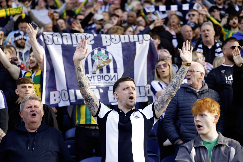 A general view of WBA fans cheering at a game with a flag in the background