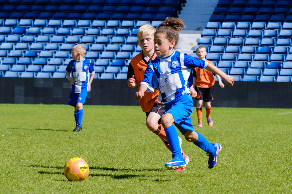Players running onto the ball, shielding off defender.
